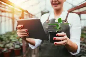 Horticultrice tenant une plante et une tablette, symbolisant la croissance personnelle.